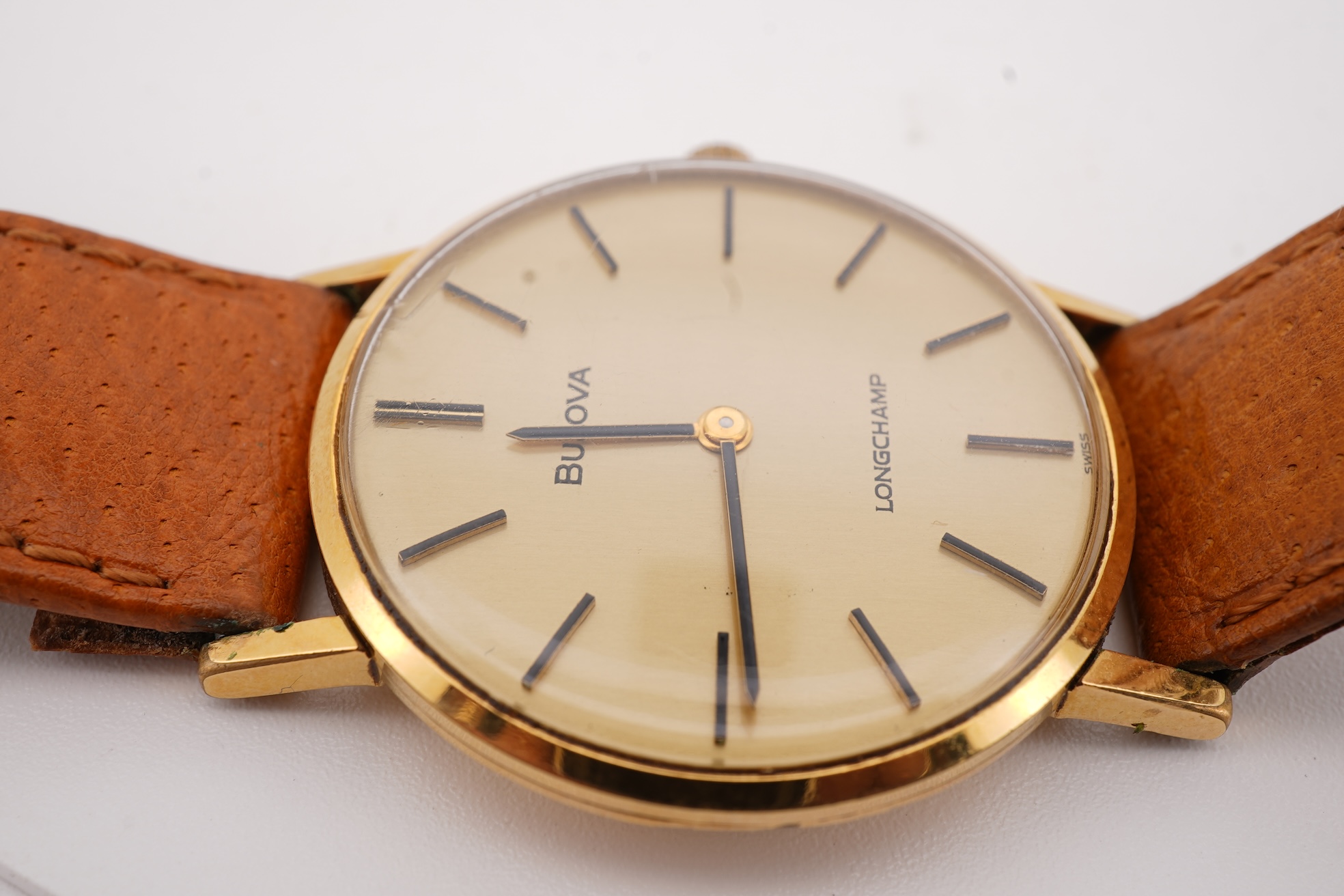 A gentleman's steel and gold plated Bulova Longchamp manual wind wrist watch, with baton numerals, case diameter 33mm, on a tanned leather strap.